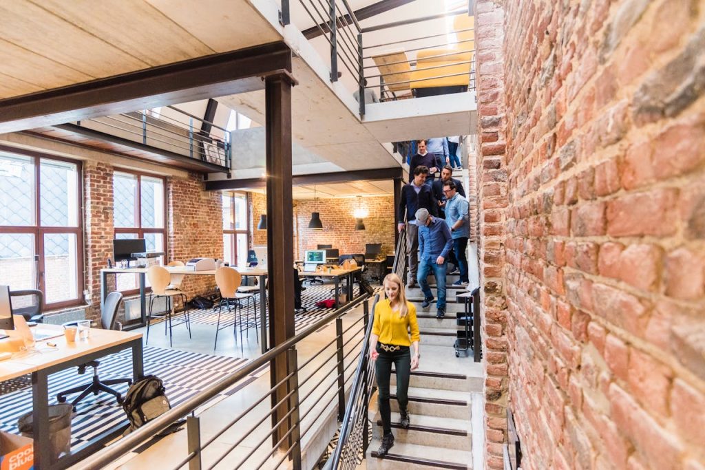 Open-concept office with brick walls, multi-level layout, and team members working together.